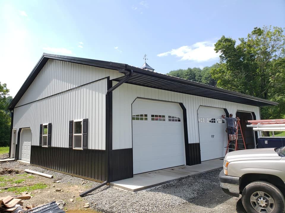 A white truck is parked in front of a black and white garage