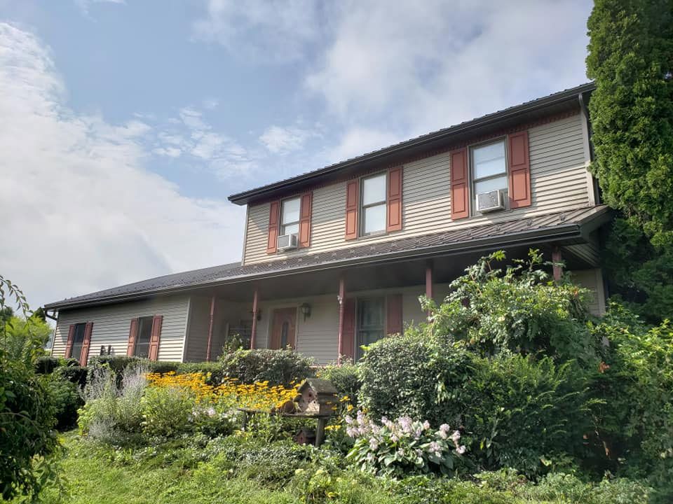 A large house with a porch is surrounded by trees and bushes.