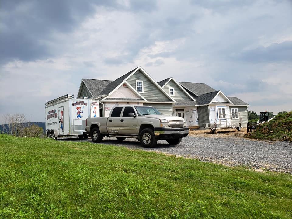 A truck is parked in front of a house with a trailer attached to it.