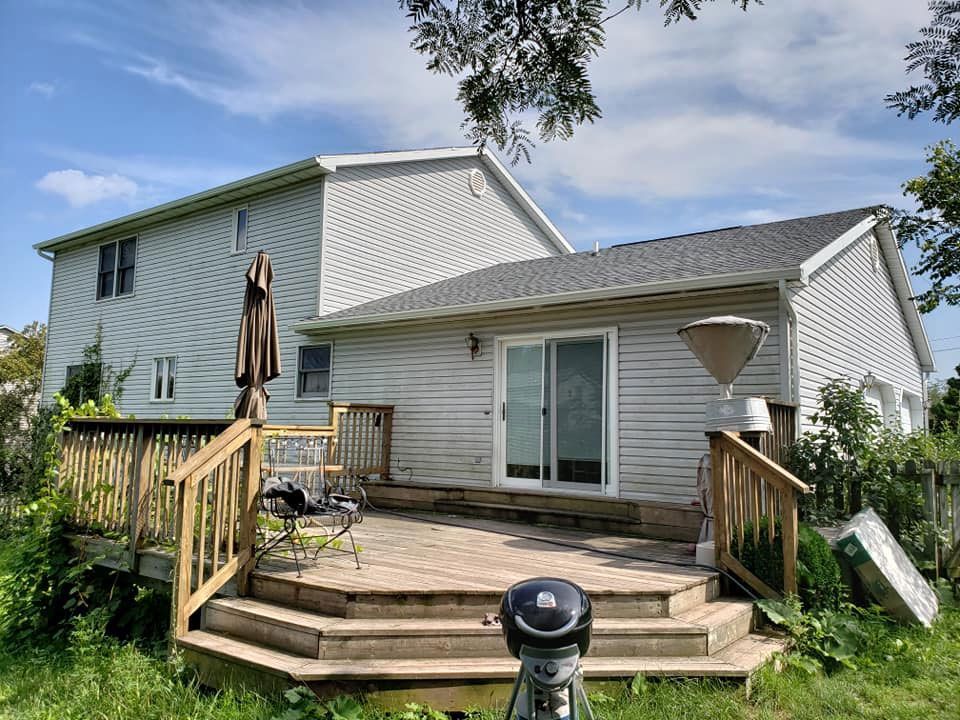 A white house with a wooden deck in front of it.