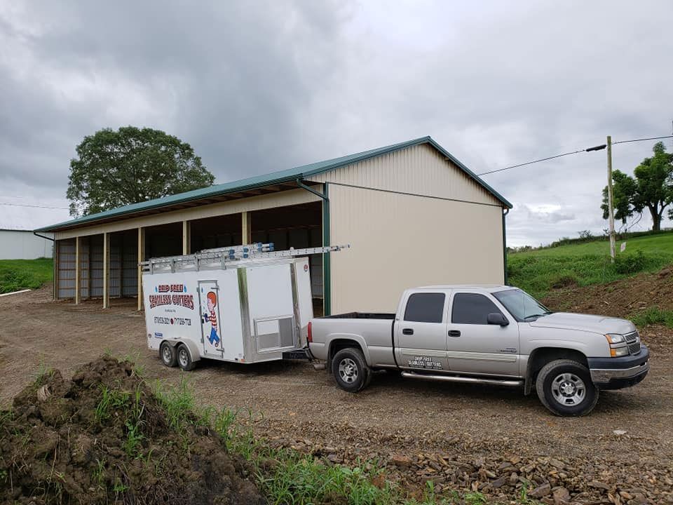 A truck with a trailer attached to it is parked in front of a building.