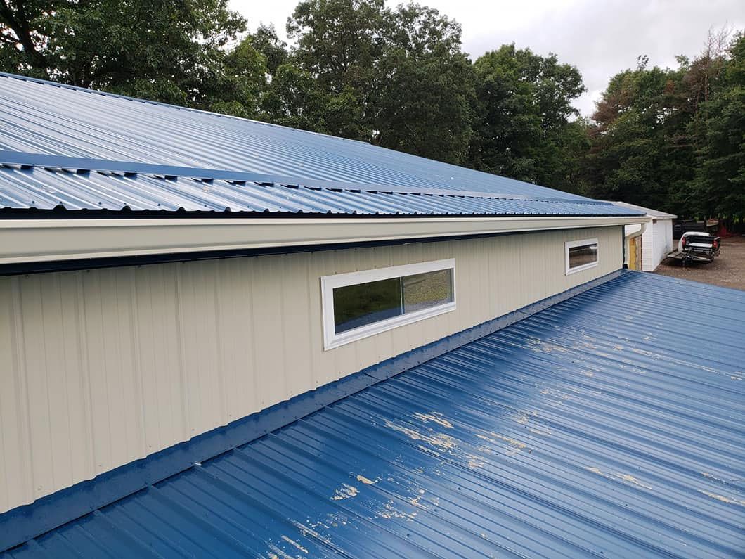A blue metal roof with a window on the side of a building.
