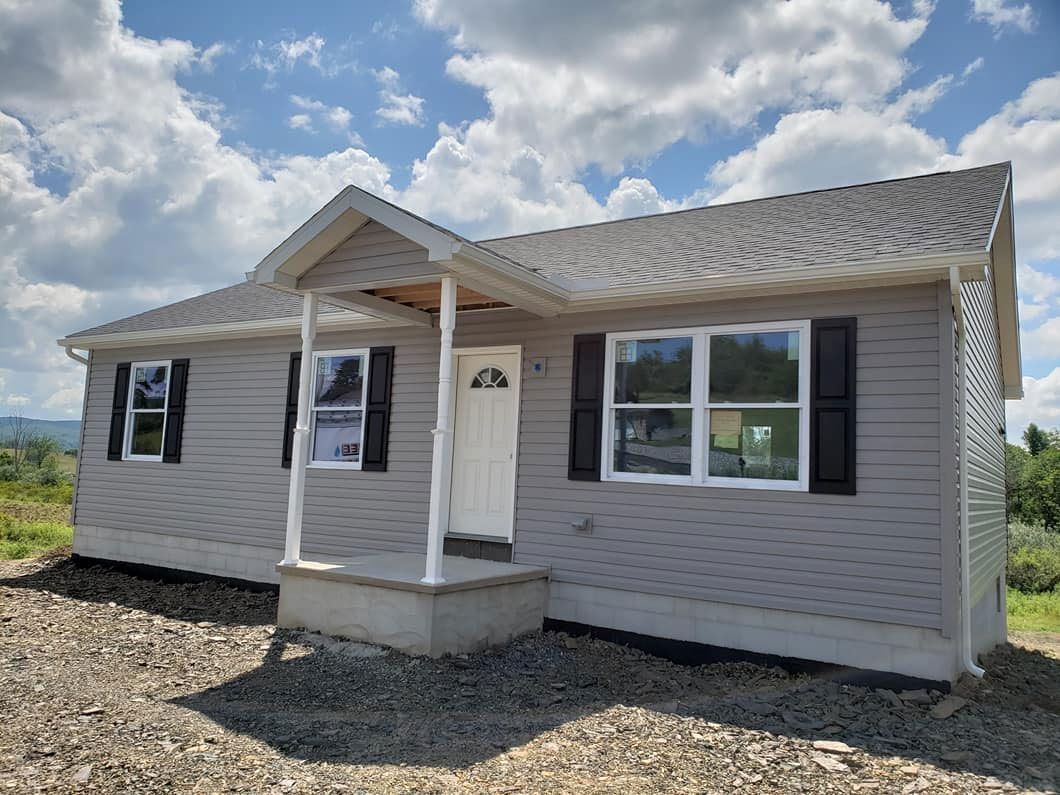 A small house with a porch and a blue sky in the background.