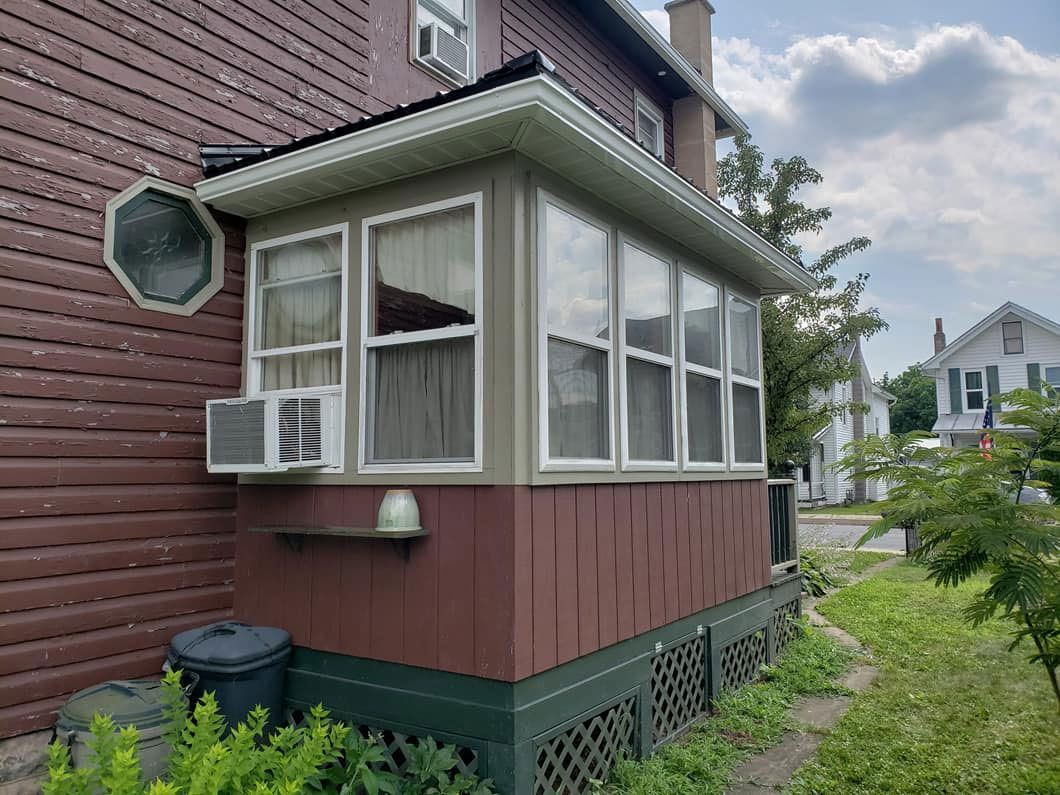 A house with a screened in porch on the side of it.
