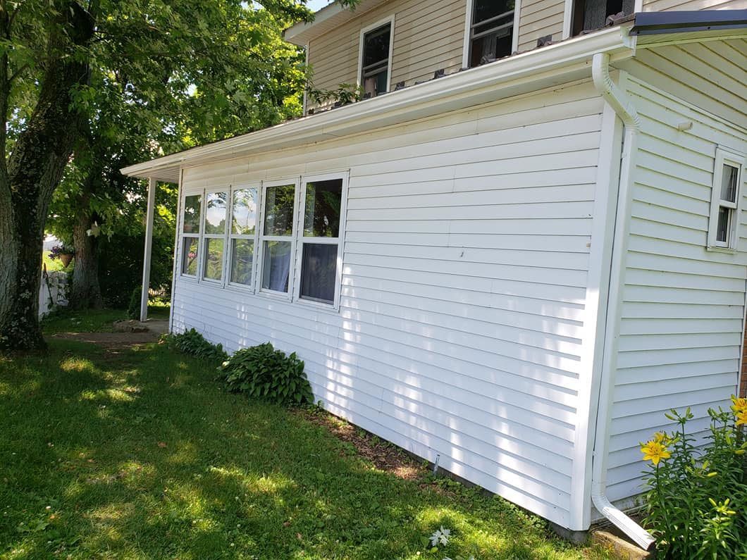 A white house with a porch and a lot of windows.