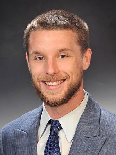 A man in a suit and tie is smiling for the camera, named Daniel Weixelbaum.