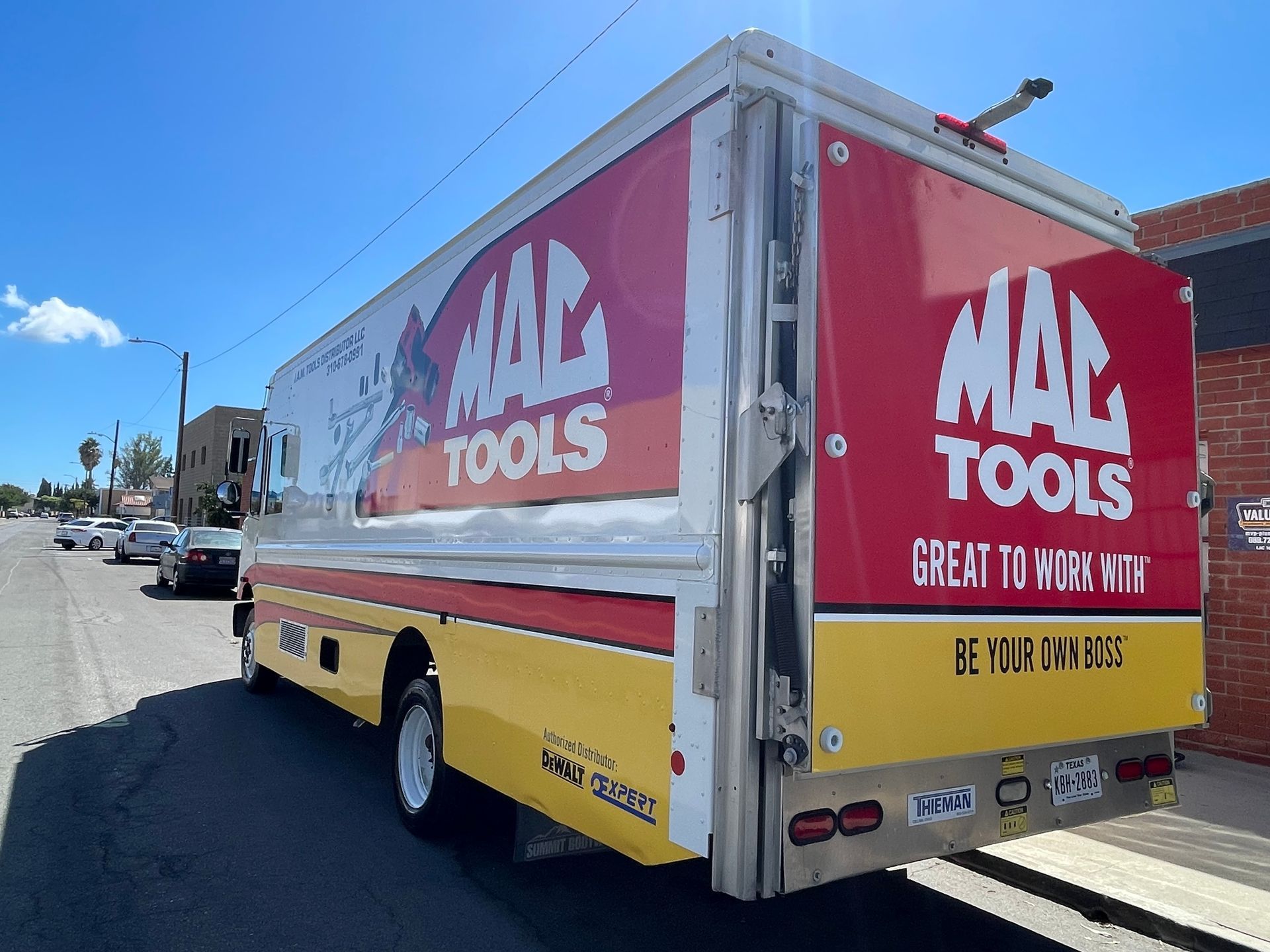 Yellow trailer with red Max Tools ad parked on a sunny street corner