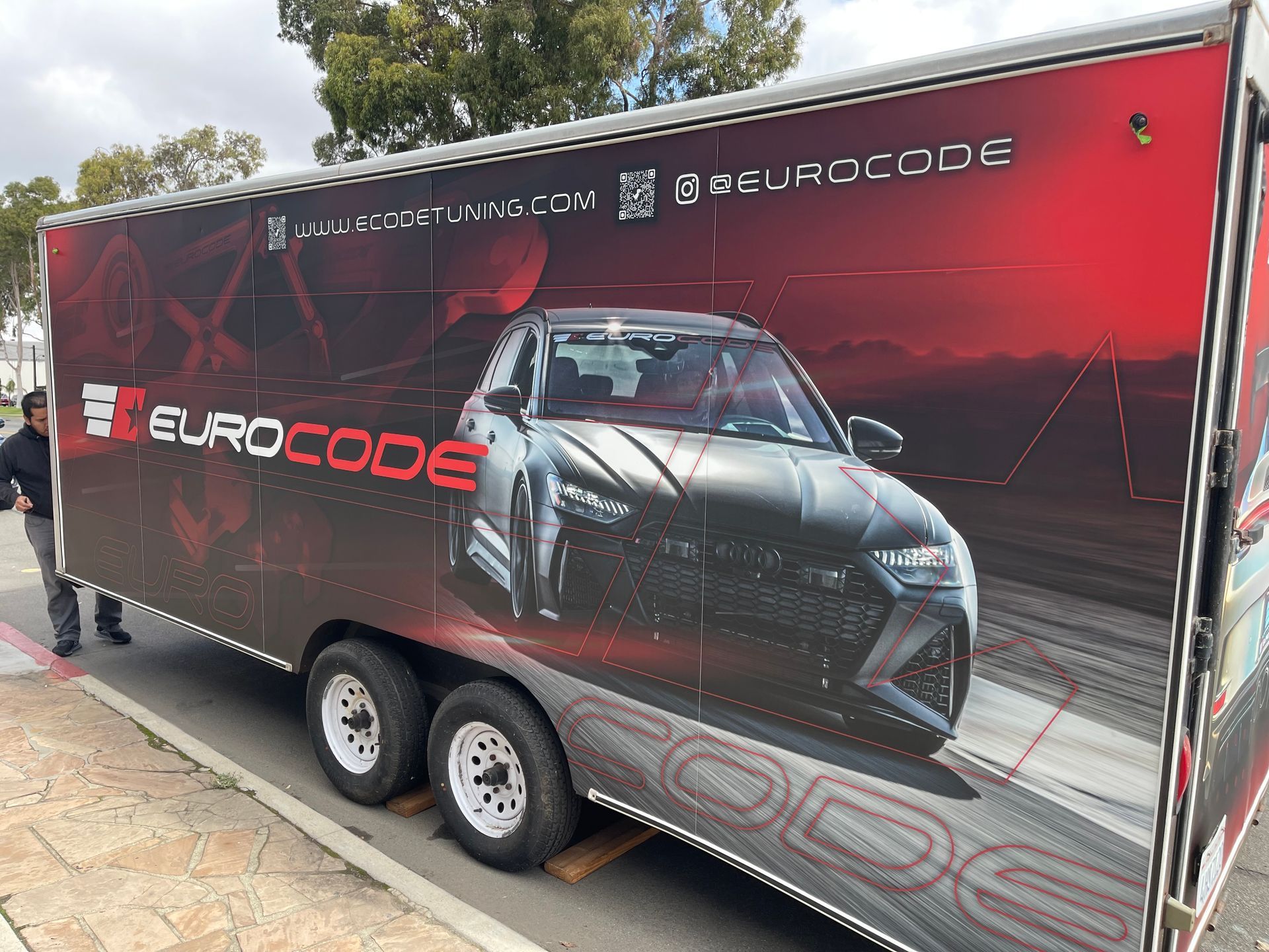 Red Eurocode car-trailer wrap with a sports car graphic parked outdoors