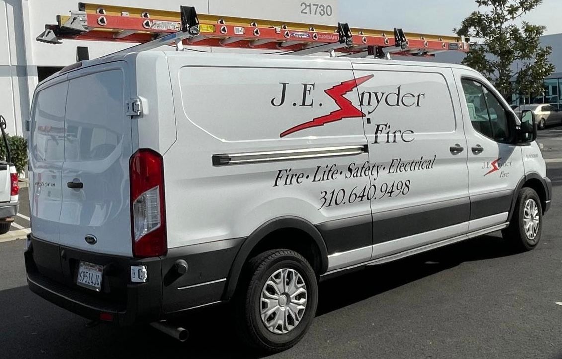 White service van with ladder racks and company logo parked on a street