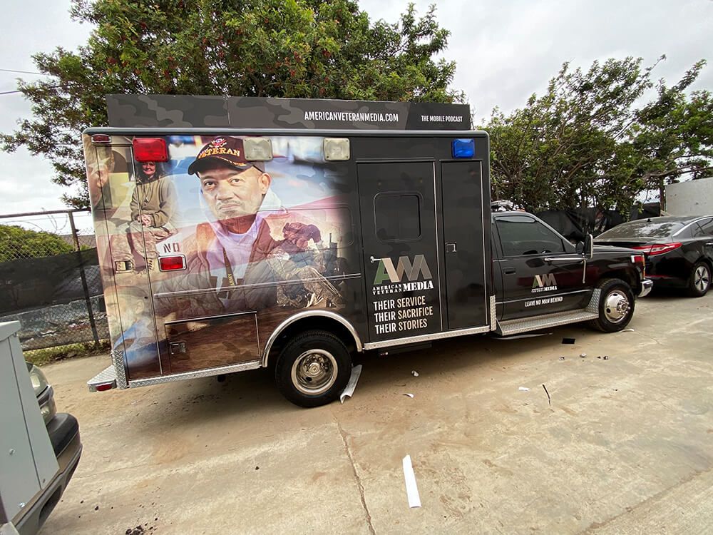 An ambulance with a picture of a man on the side is parked in a parking lot.