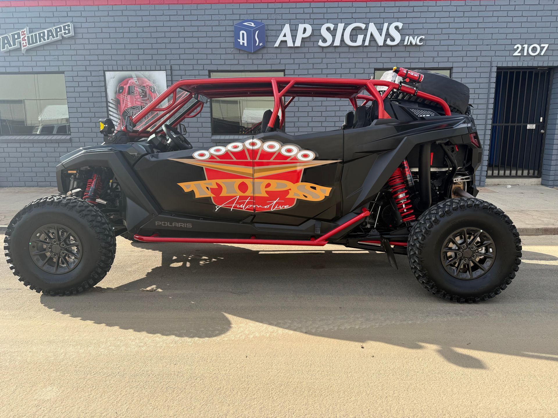 Black and red UTV with custom graphics parked in front of AP Signs building.