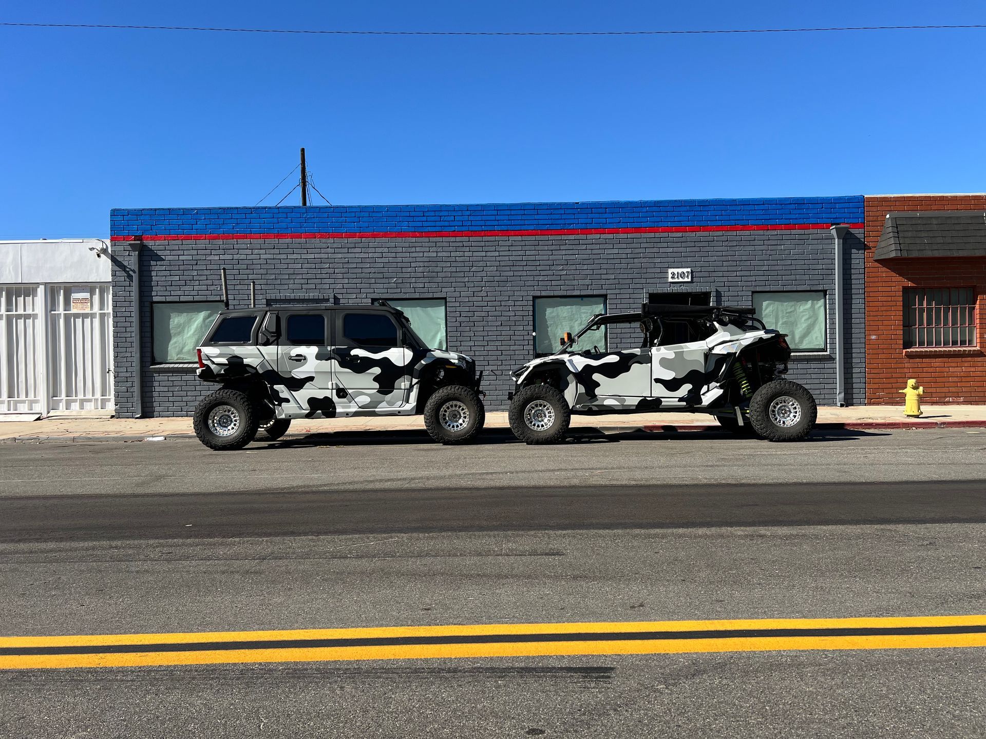 Two atvs are parked on the side of the road in front of a building.