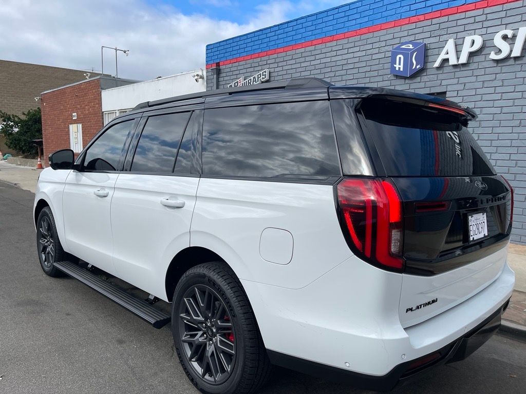 White SUV parked on a street in front of a business. Black accents, tinted windows, and a Platinum badge are visible.