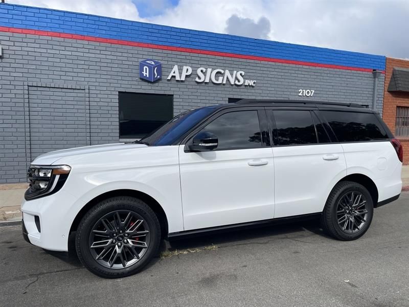 White Ford Expedition parked in front of a sign shop with