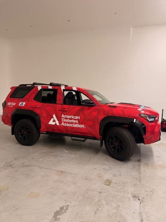 Red Toyota SUV with black wheels, American Diabetes Association branding, indoors.