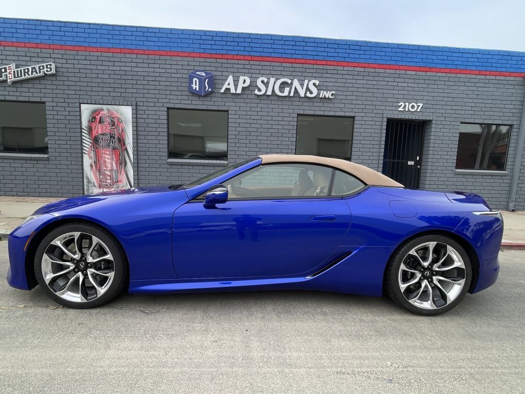Blue sports coupe parked in front of AP Signs building