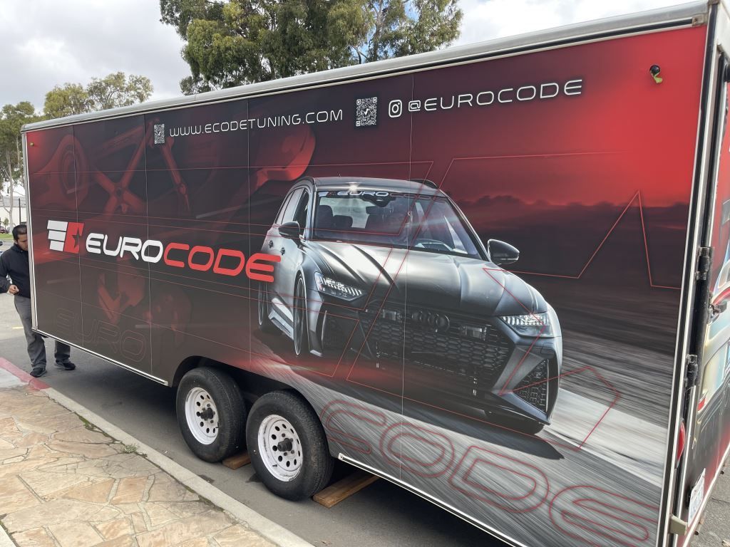 Red Eurocode trailer with a sports car graphic parked outdoors