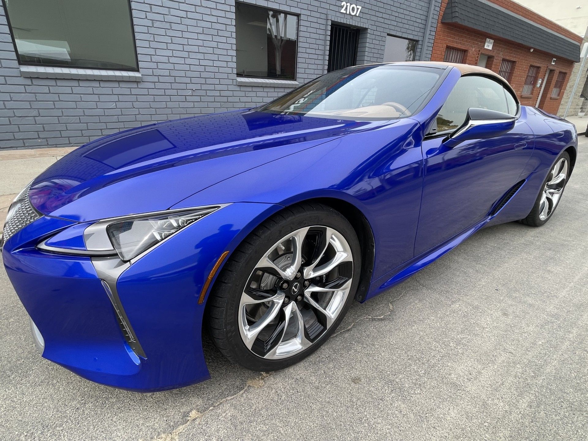 Blue sports car parked on a street beside a brick building