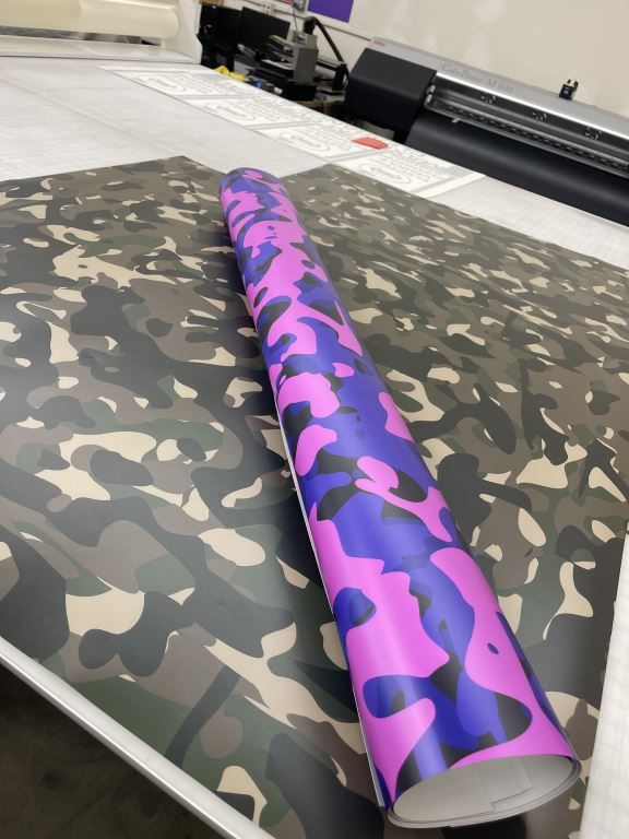 Purple and pink patterned roll of material on a camouflage-print table in a workshop
