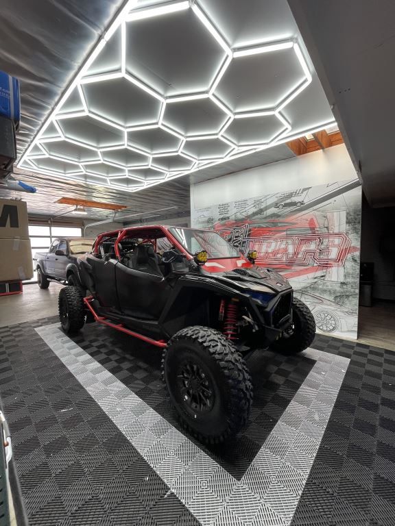 Black off-road buggy displayed indoors beneath hexagonal ceiling lights