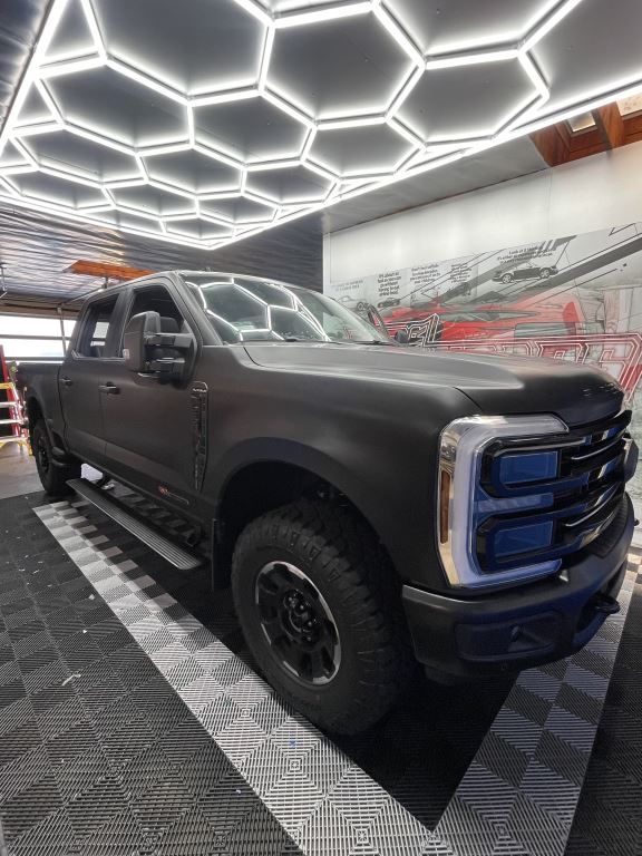 Black lifted pickup truck in a garage with bright hexagonal ceiling lights