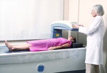 doctor-examining-woman-in-40s-at-Bone-Densitometer-Machine