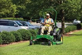 A man is riding a lawn mower on a lush green lawn