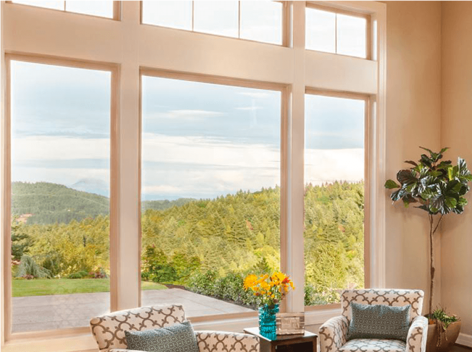 Living room with large windows overlooking a green, mountainous landscape. Two patterned armchairs sit inside.