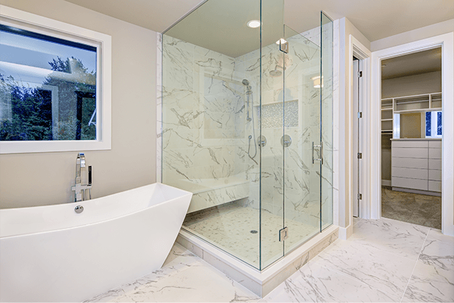 Modern white bathroom with a glass shower, a bathtub, and marble tile.