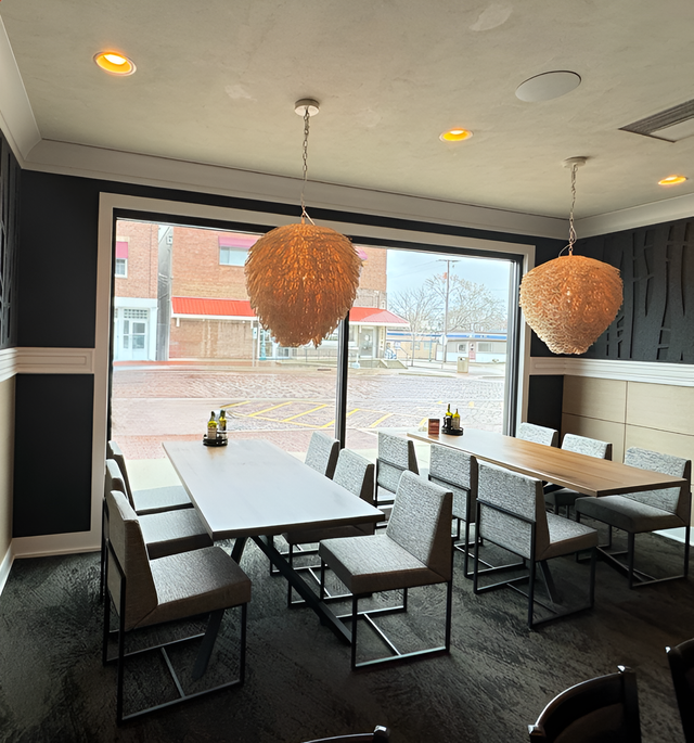Dining room with tables, chairs, and large window; two spherical light fixtures hang above.