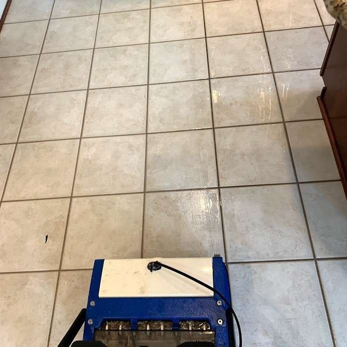 Tile floor being cleaned by a blue and white machine.