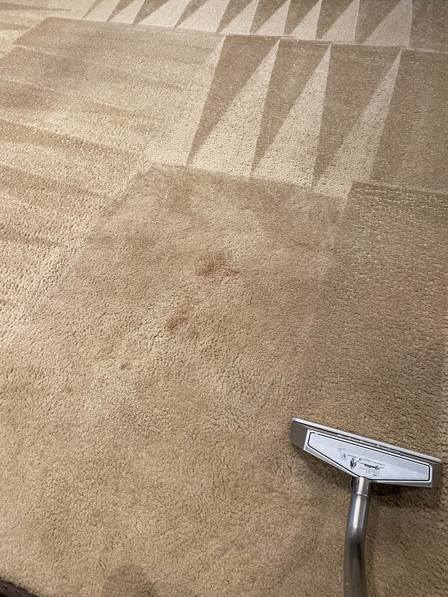 Carpet with a red stain being cleaned by a professional cleaner.