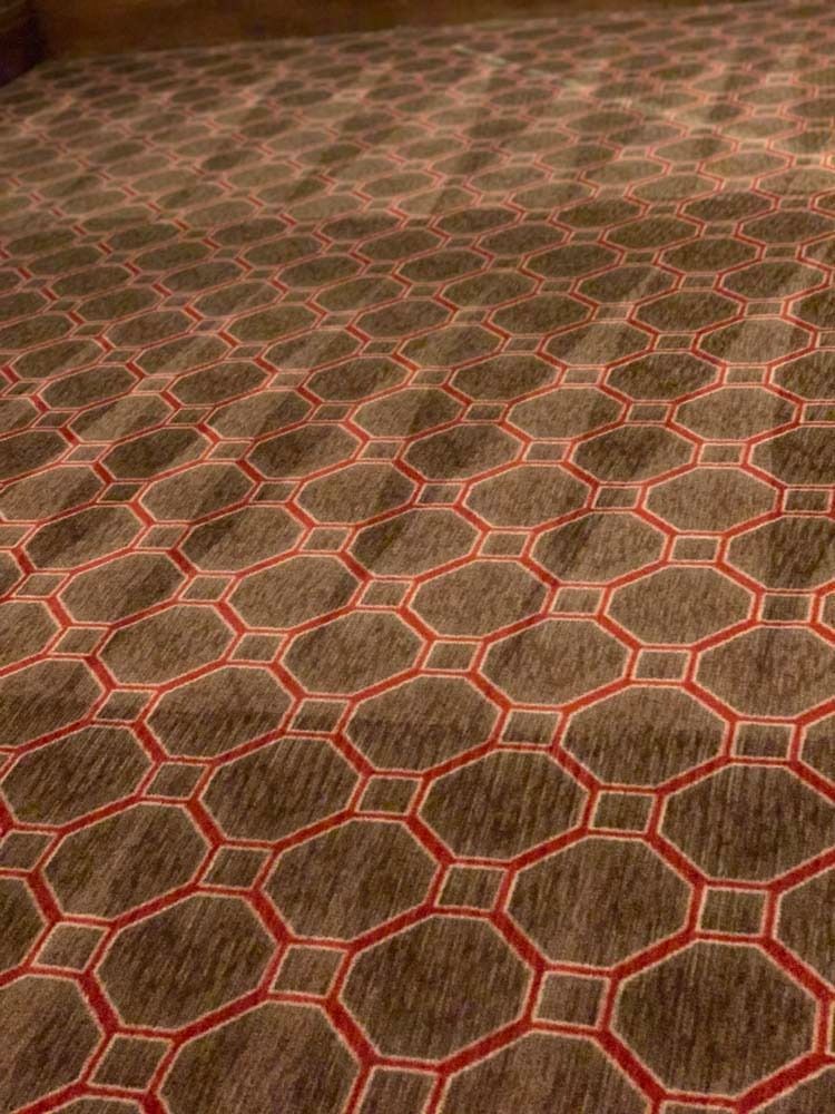 Brown carpet with a red octagonal geometric pattern.