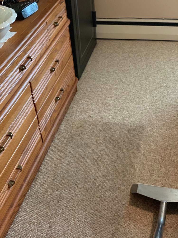 Carpet cleaning in progress near a wooden dresser.