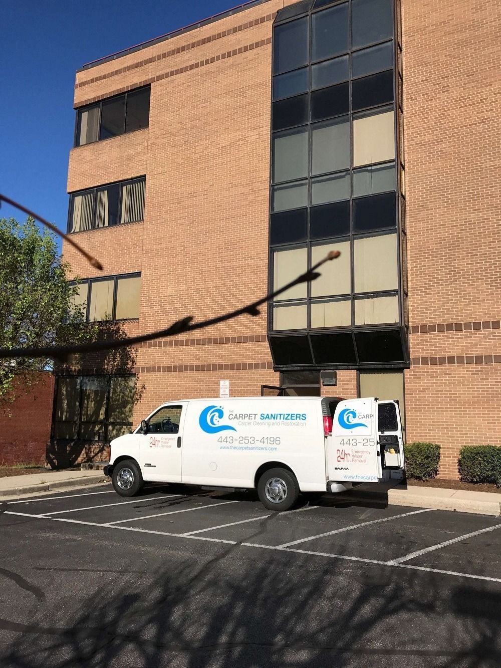 White service van parked in front of a brick building. The van has the company name 