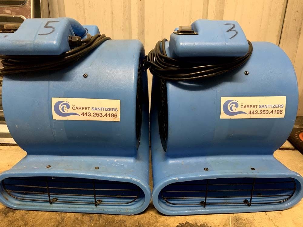 Two blue carpet fan dryers labeled 5 and 3. They have coiled black power cords and business stickers.