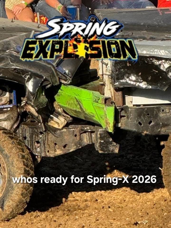 Damaged car at Spring Explosion, green and black metal, muddy tires, event banner, 