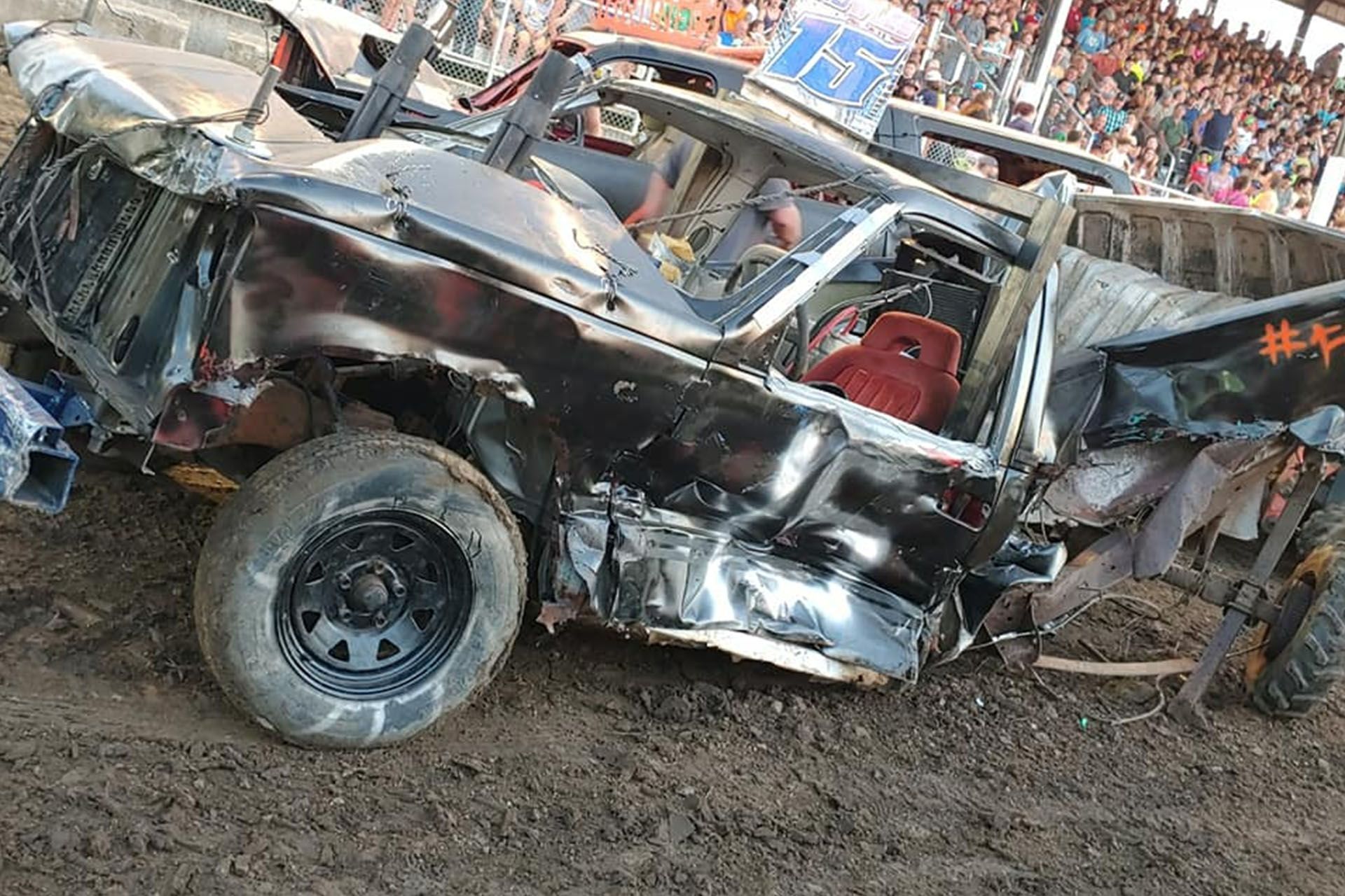A very damaged car is laying on the ground in the dirt