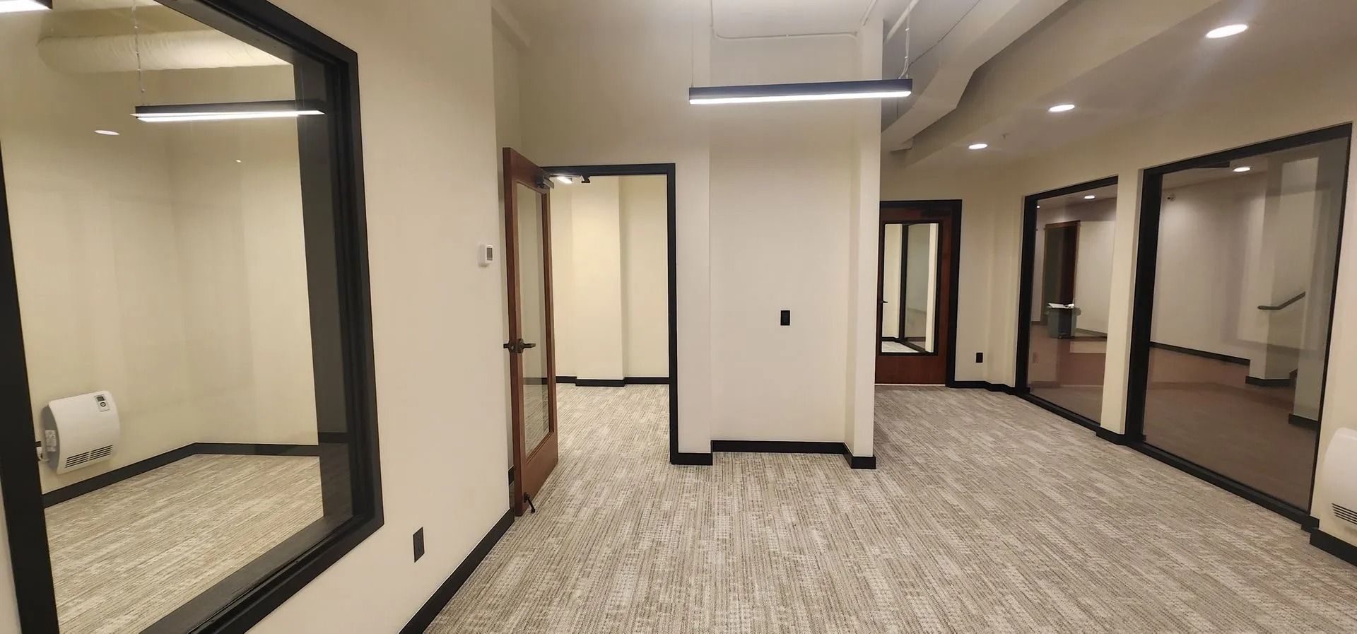 Interior office space with multiple doorways and glass walls, neutral color scheme, and patterned carpet.