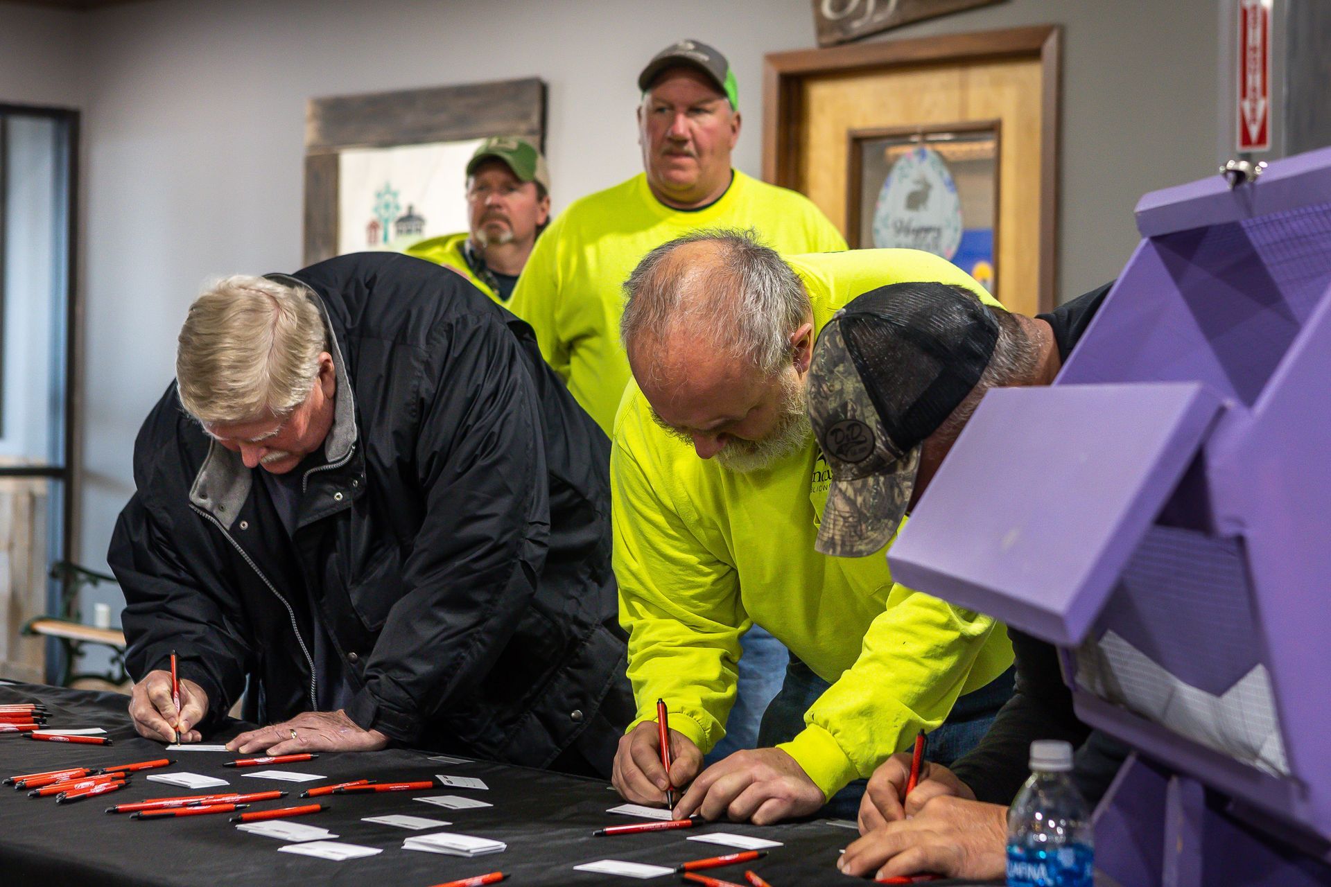 A group of men are signing papers on a table.