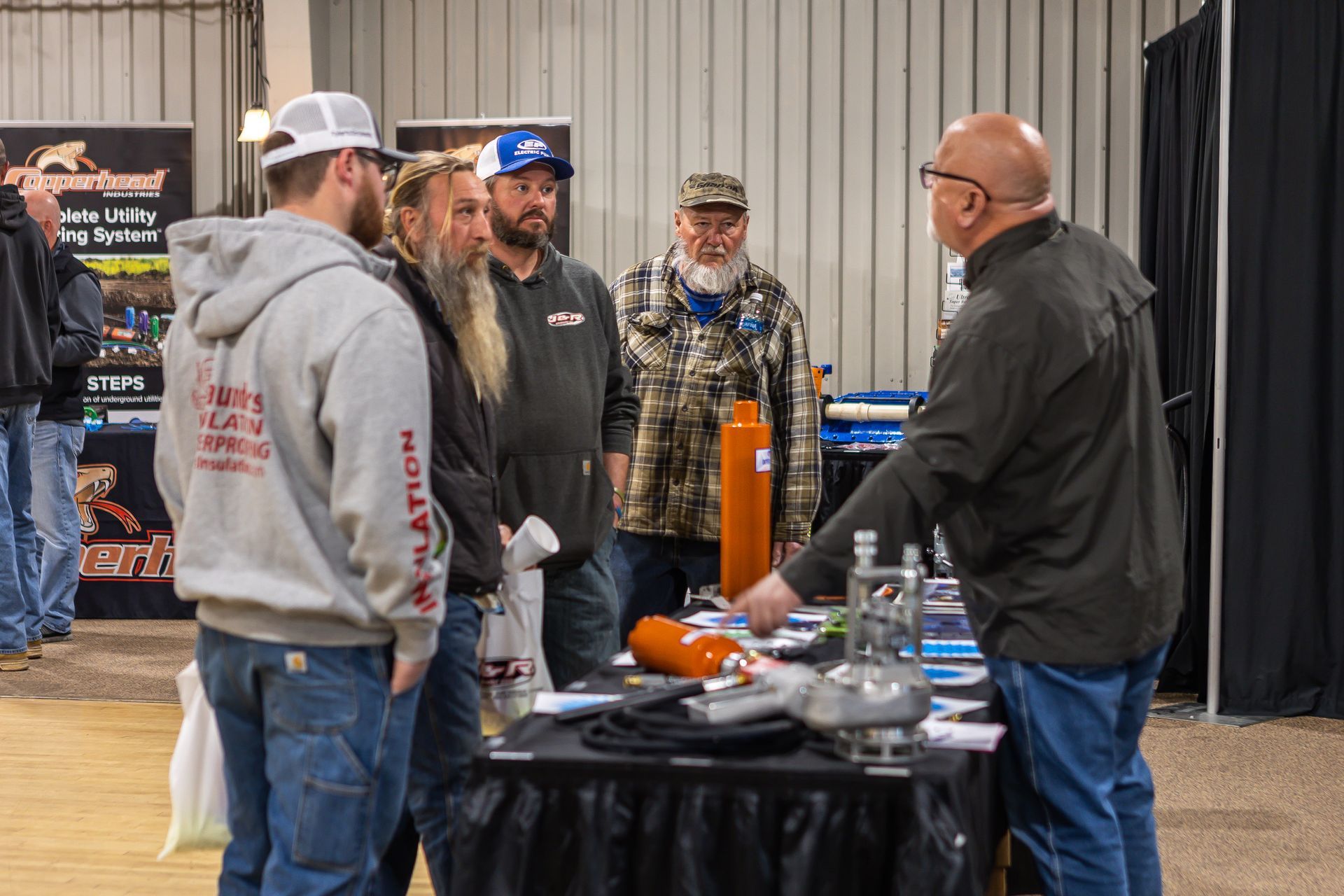 A group of men are standing around a table talking to a man.