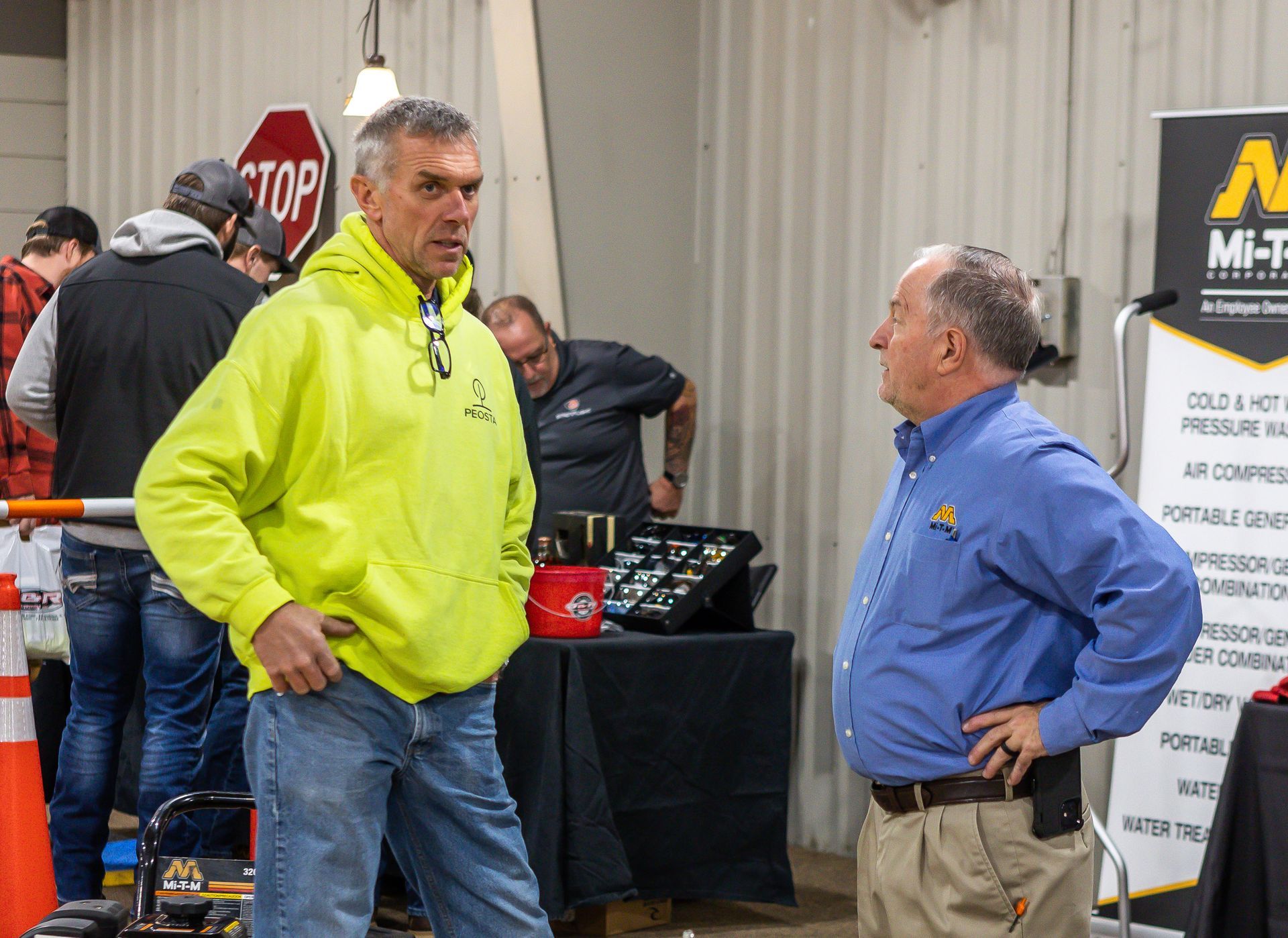 Two men are talking to each other in front of a stop sign.