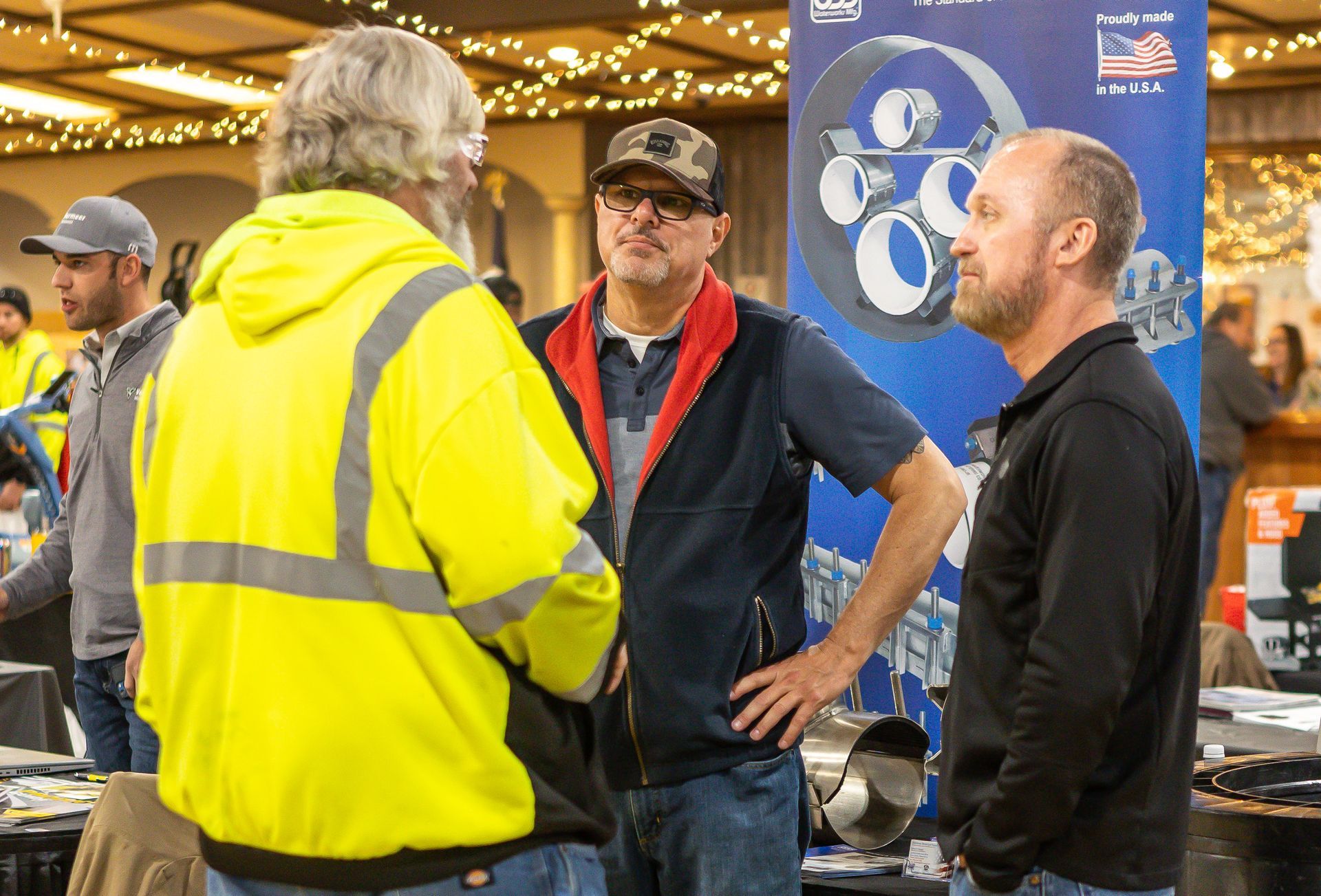 A group of men are standing in a room talking to each other.