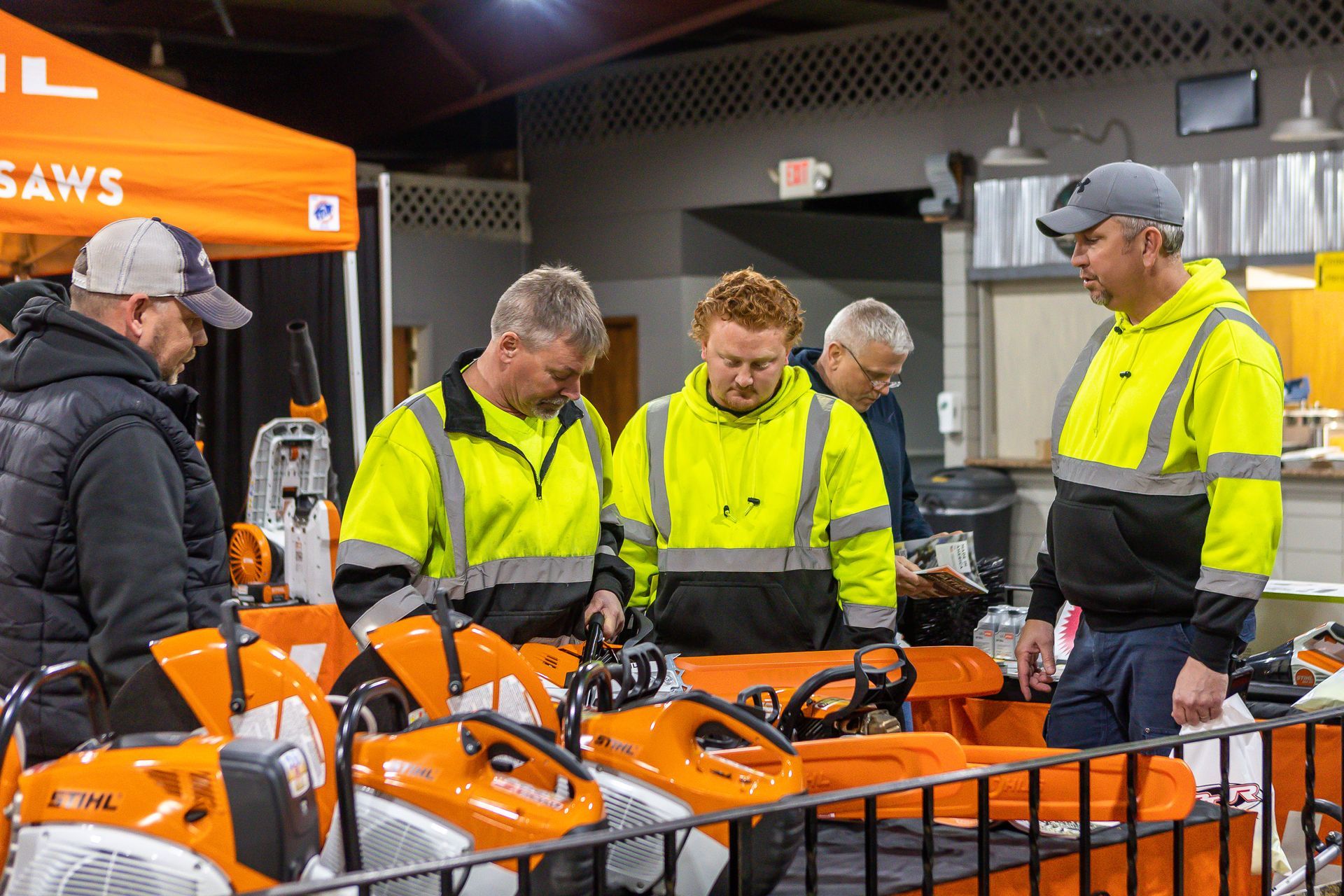 A group of men are standing around a display of Stihl saws.