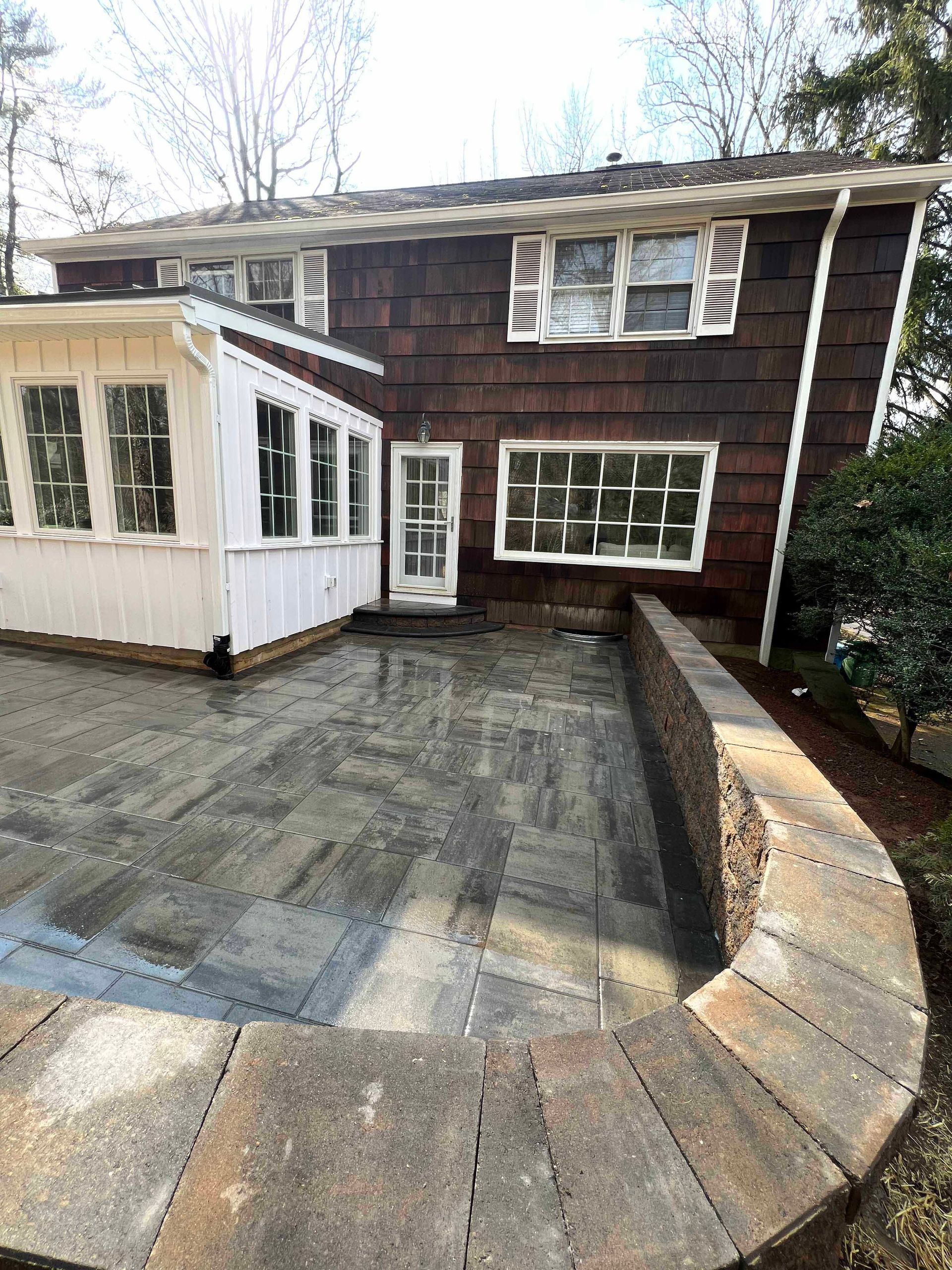 A large brown house with a patio in front of it.
