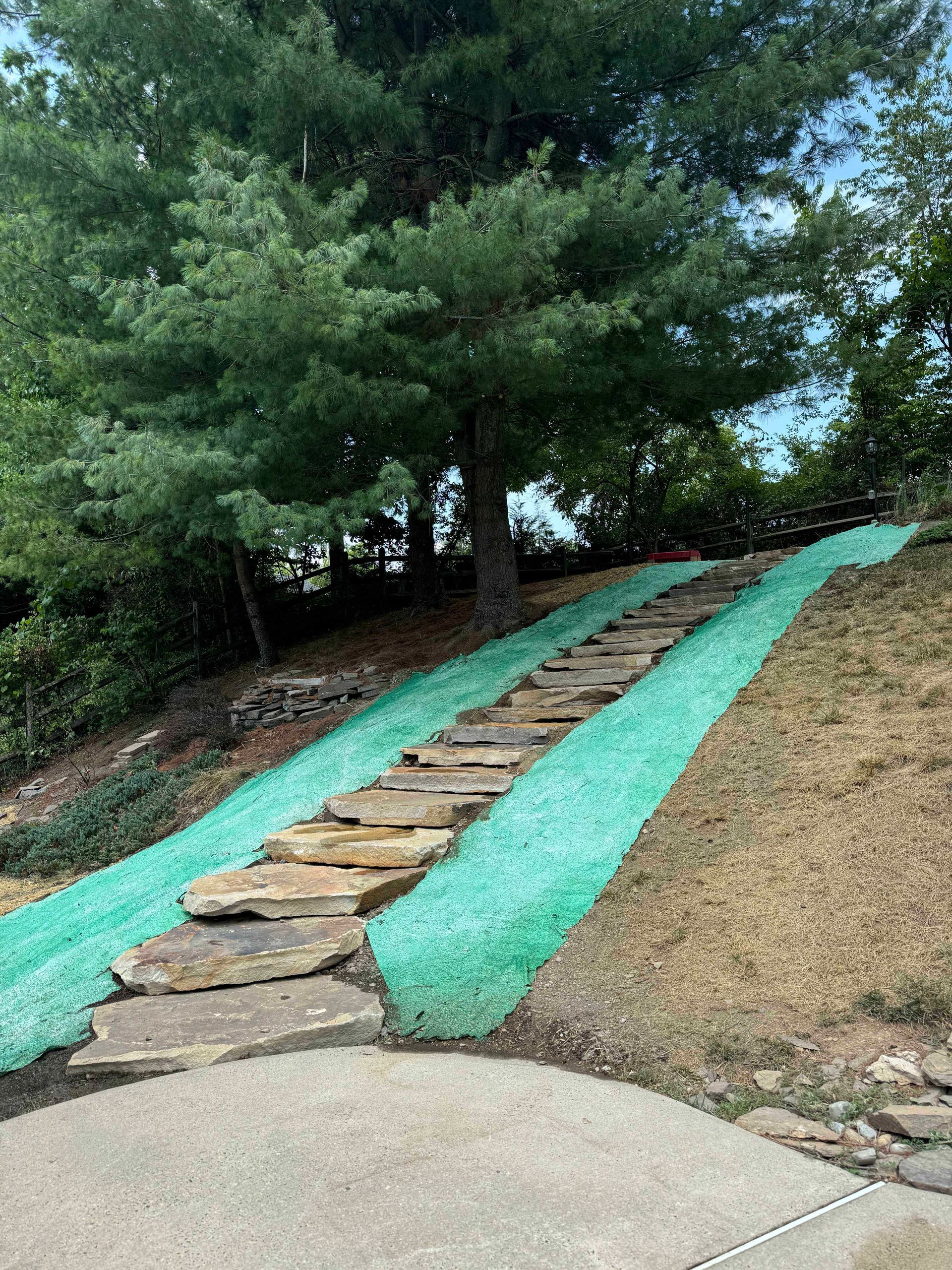 A stone walkway going up a hill covered in green grass.