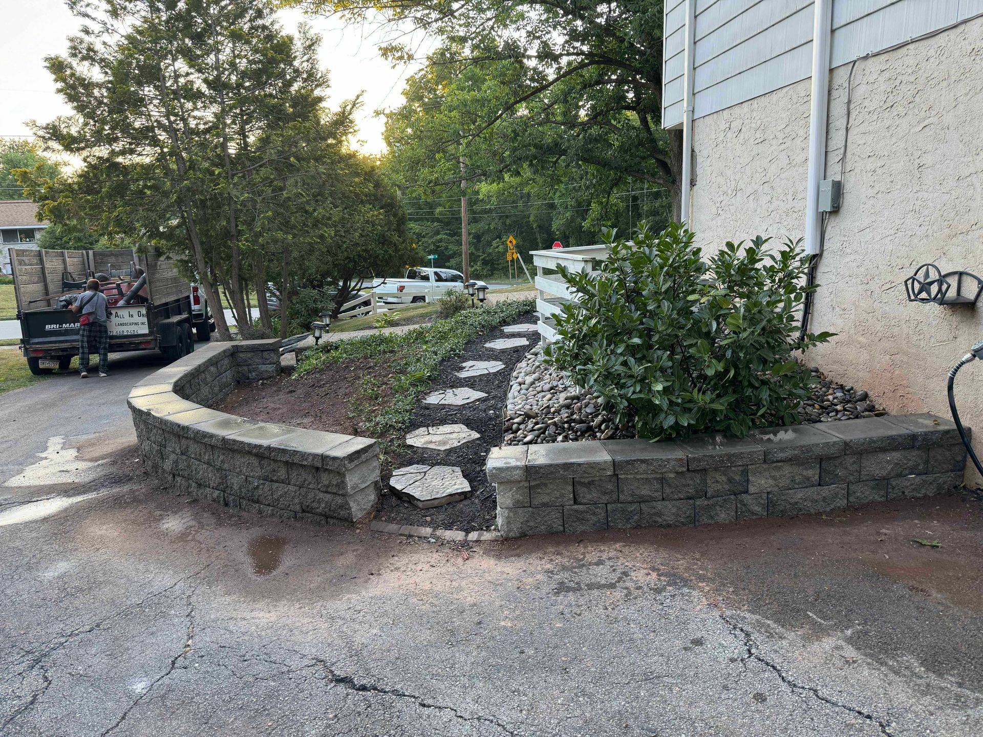 A jeep is parked in the driveway of a house next to a stone wall.