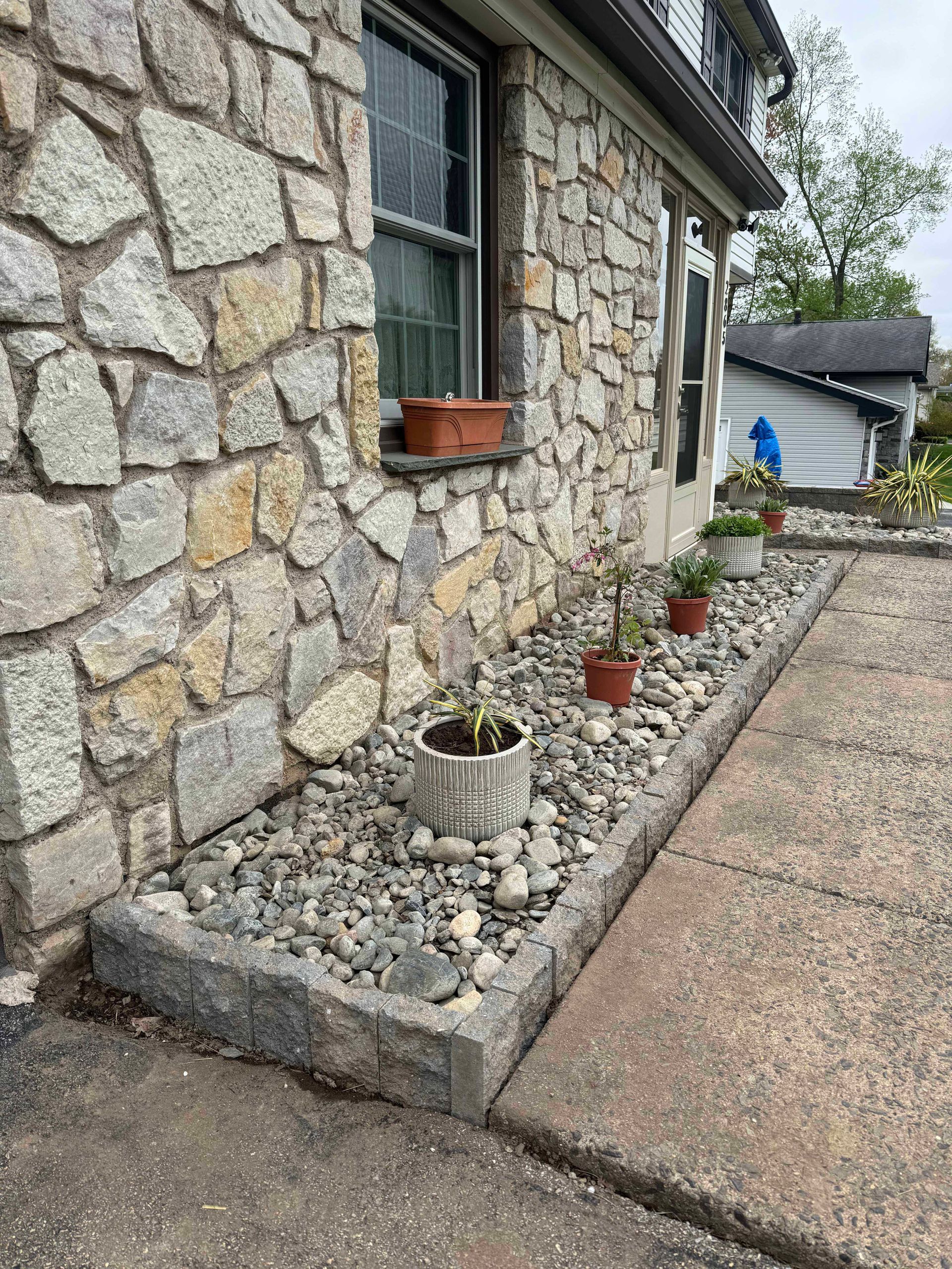 A stone wall with potted plants in front of it.