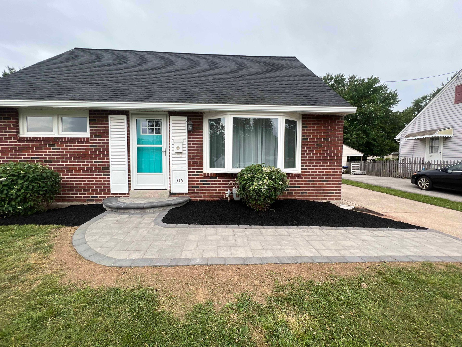 A small brick house with a walkway leading to it and a car parked in front of it.