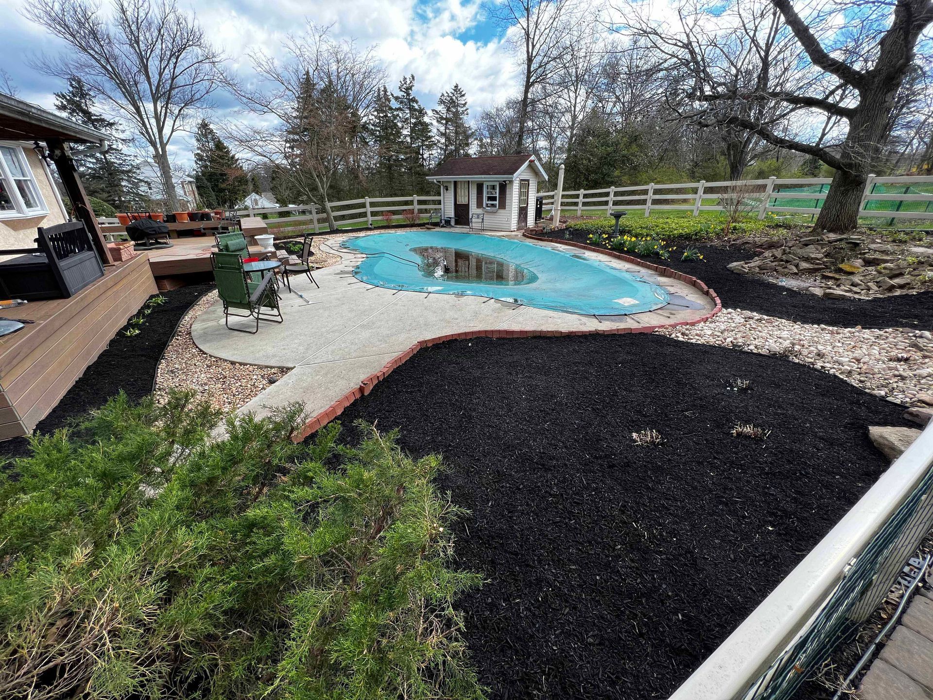 A large swimming pool is in the backyard of a house.